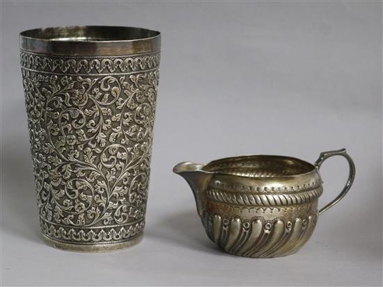 An Indian embossed white metal beaker and a Victorian silver cream jug.